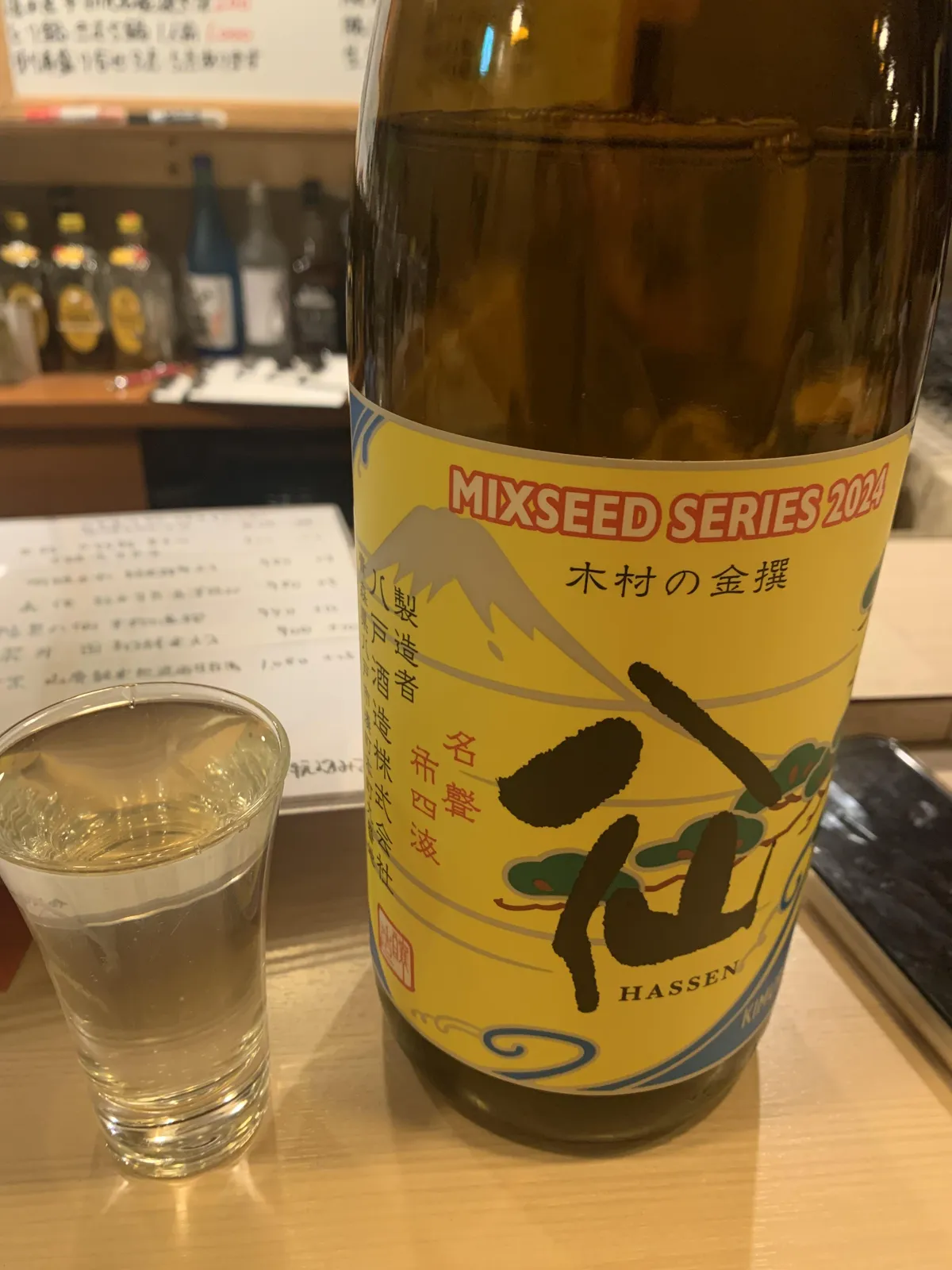陸奥八仙 Mixseed Series 2024 木村の金撰のボトルと、お酒の注がれたグラス