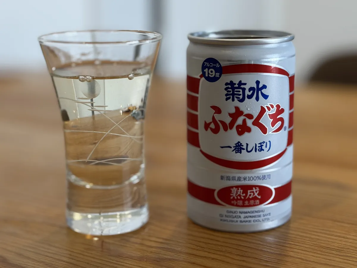 菊水熟成ふなぐちの缶と、グラスに注がれた黄金色のお酒