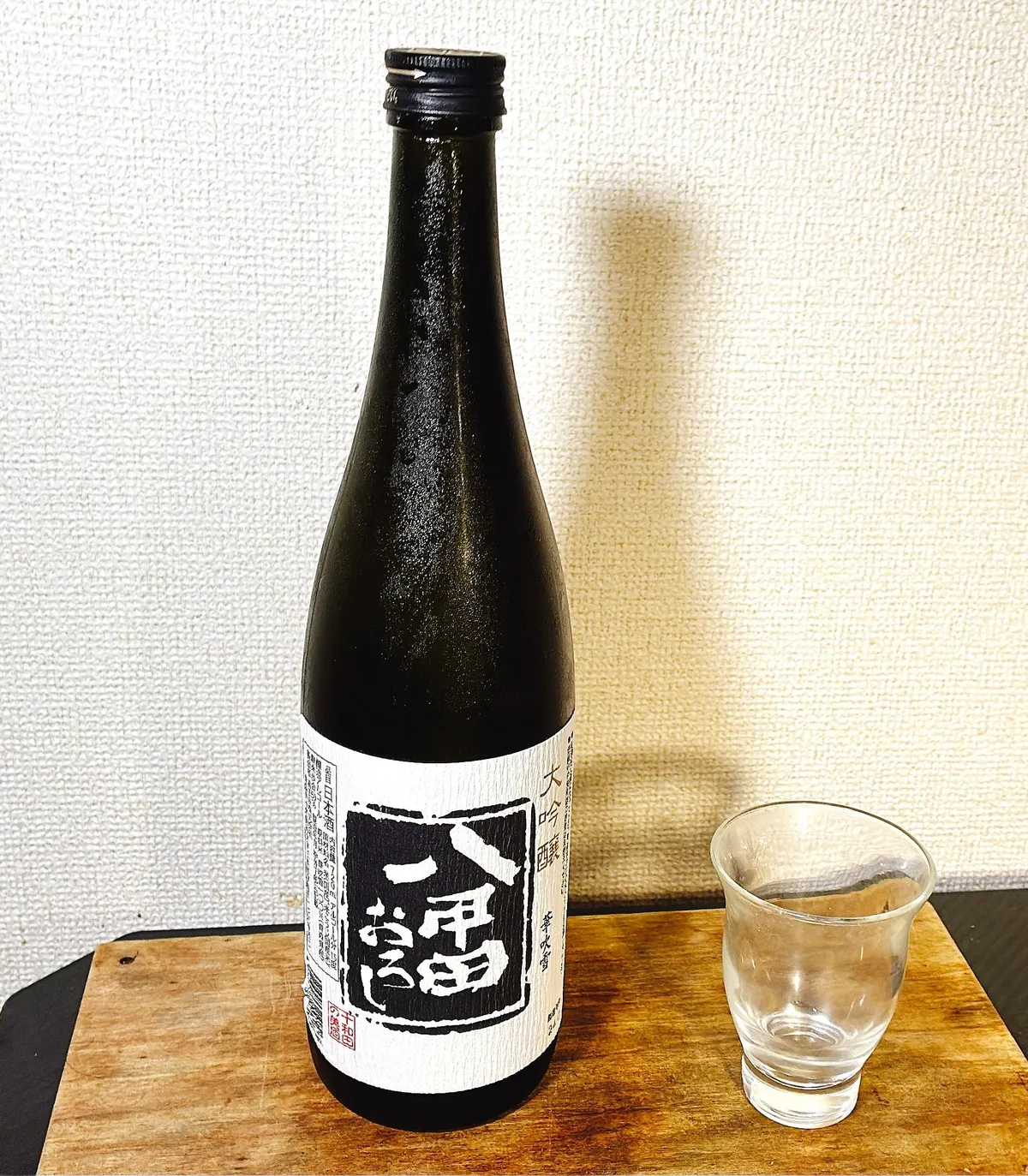 木目のボードに置かれた八甲田おろしの大吟醸ボトルと冷酒グラス