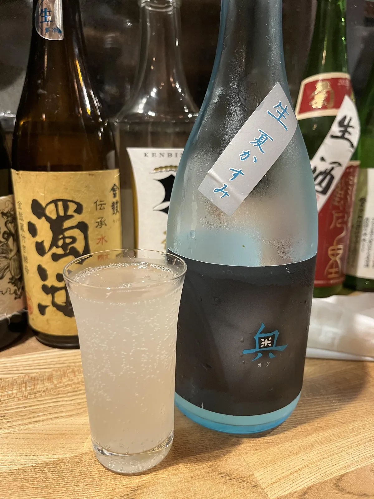 結露したブルーのボトルと、薄濁りのお酒が注がれたグラス