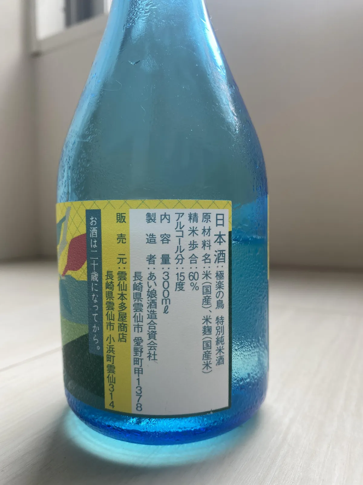 極楽の鳥の裏ラベル。結露した青いボトルに原材料などが記されている