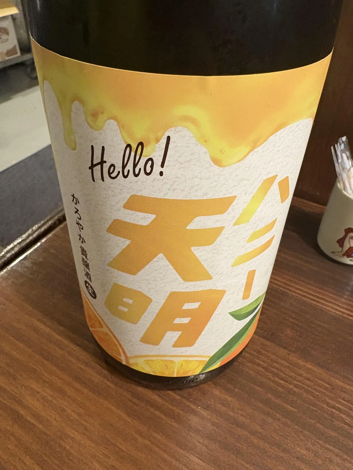 Hello! ハニー天明 かろやか貴醸酒のボトル正面。はちみつが垂れているような黄色いデザインが特徴的