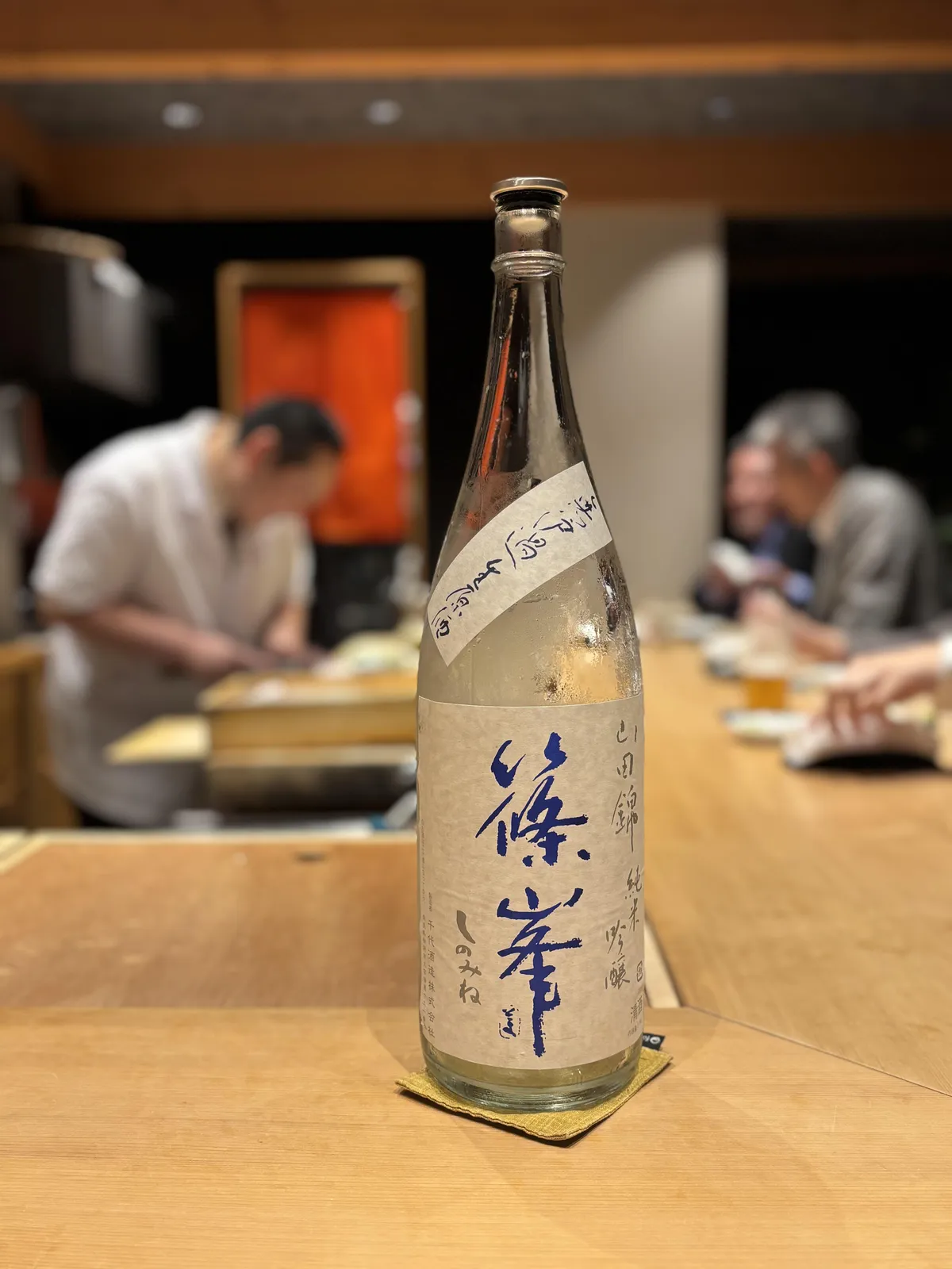 お鮨屋さんのカウンターに置かれた、冷えて水滴のついた篠峯のボトル