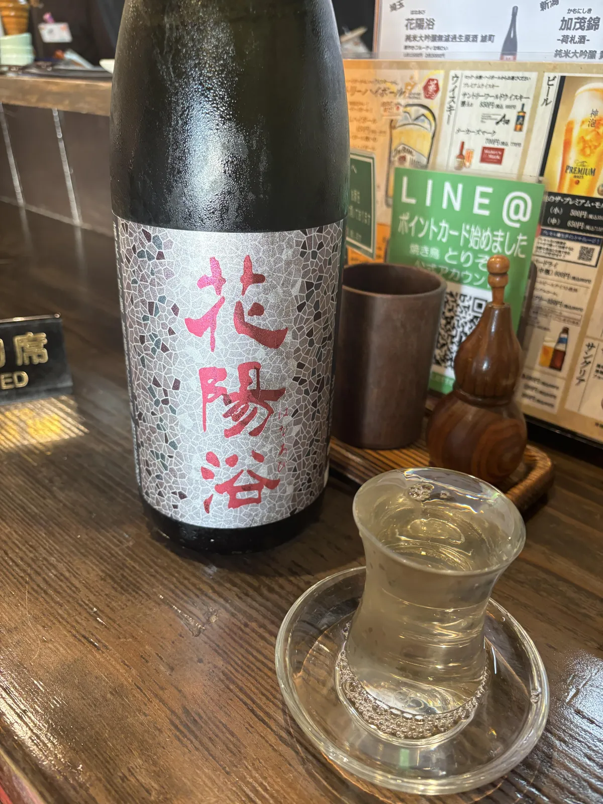 カウンターに置かれた花陽浴のボトルと、なみなみと注がれたお酒の入ったグラス