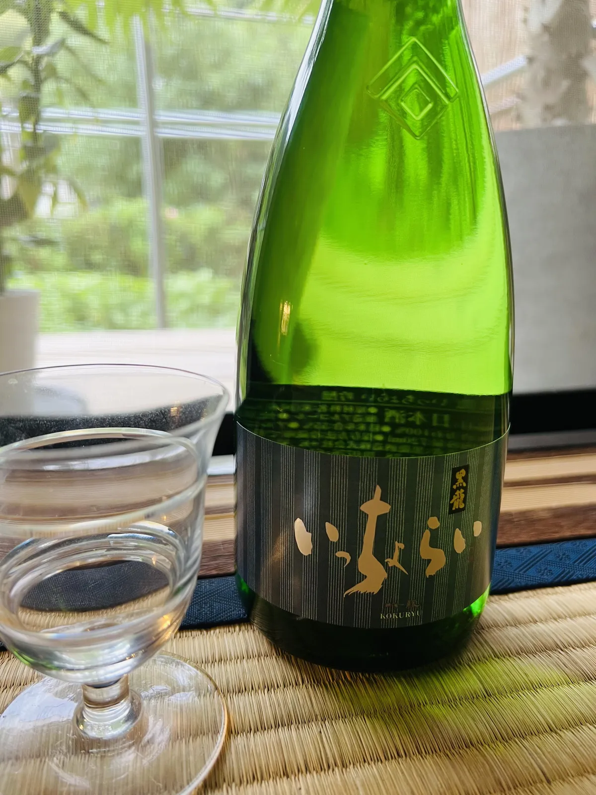 畳の上に置かれた黒龍 いっちょらいのボトルとグラス