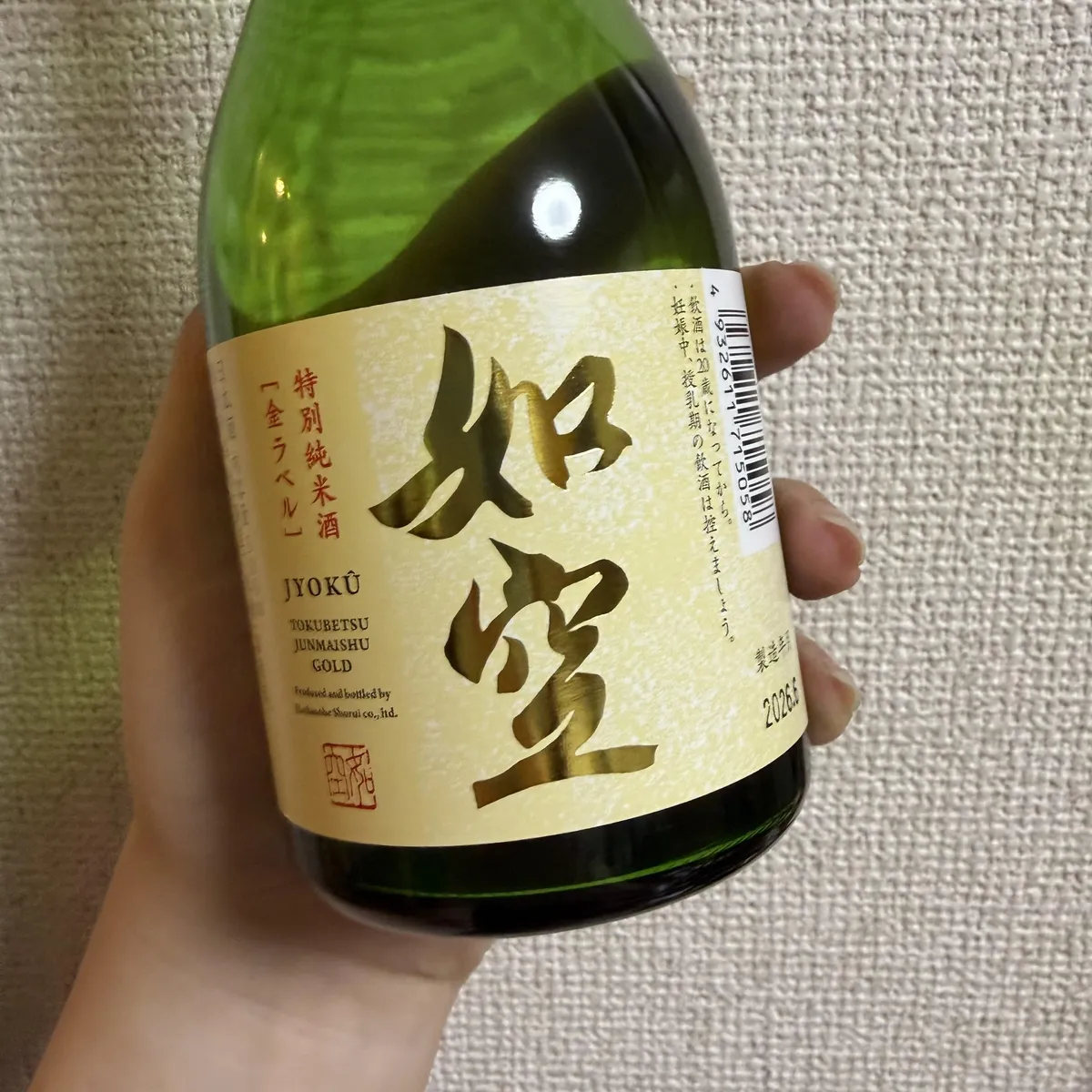 如空 特別純米酒 金ラベルのボトルを手に持った様子