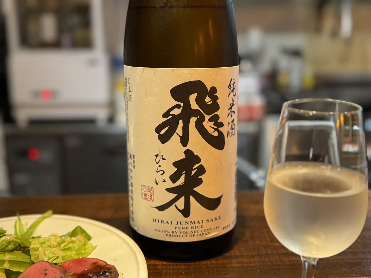 ワイングラスに注がれた純米酒 飛来と、手前に添えられた鹿肉のロースト