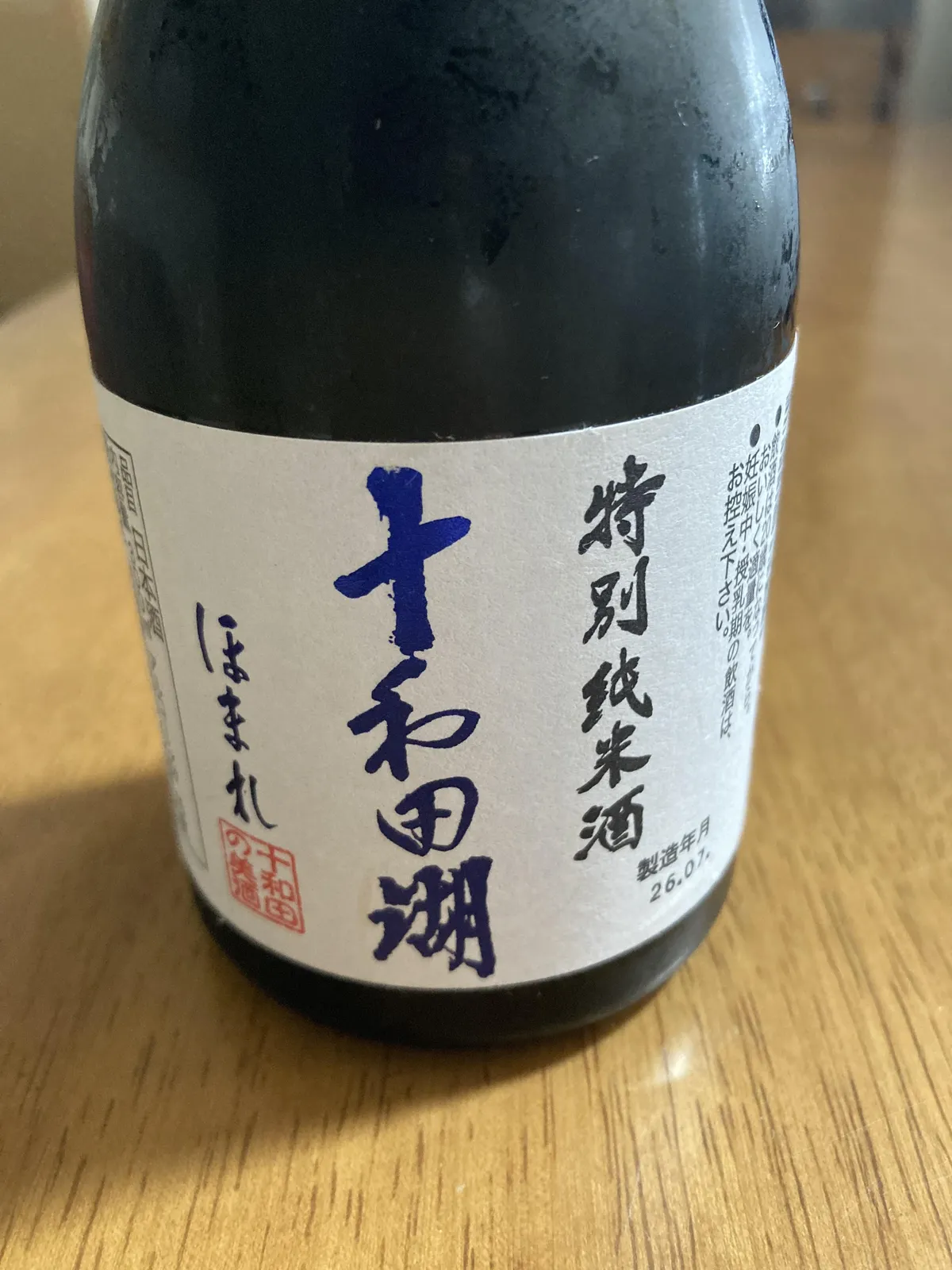 特別純米酒 十和田湖ほまれのボトル正面。白地に青い筆文字が映えるラベル