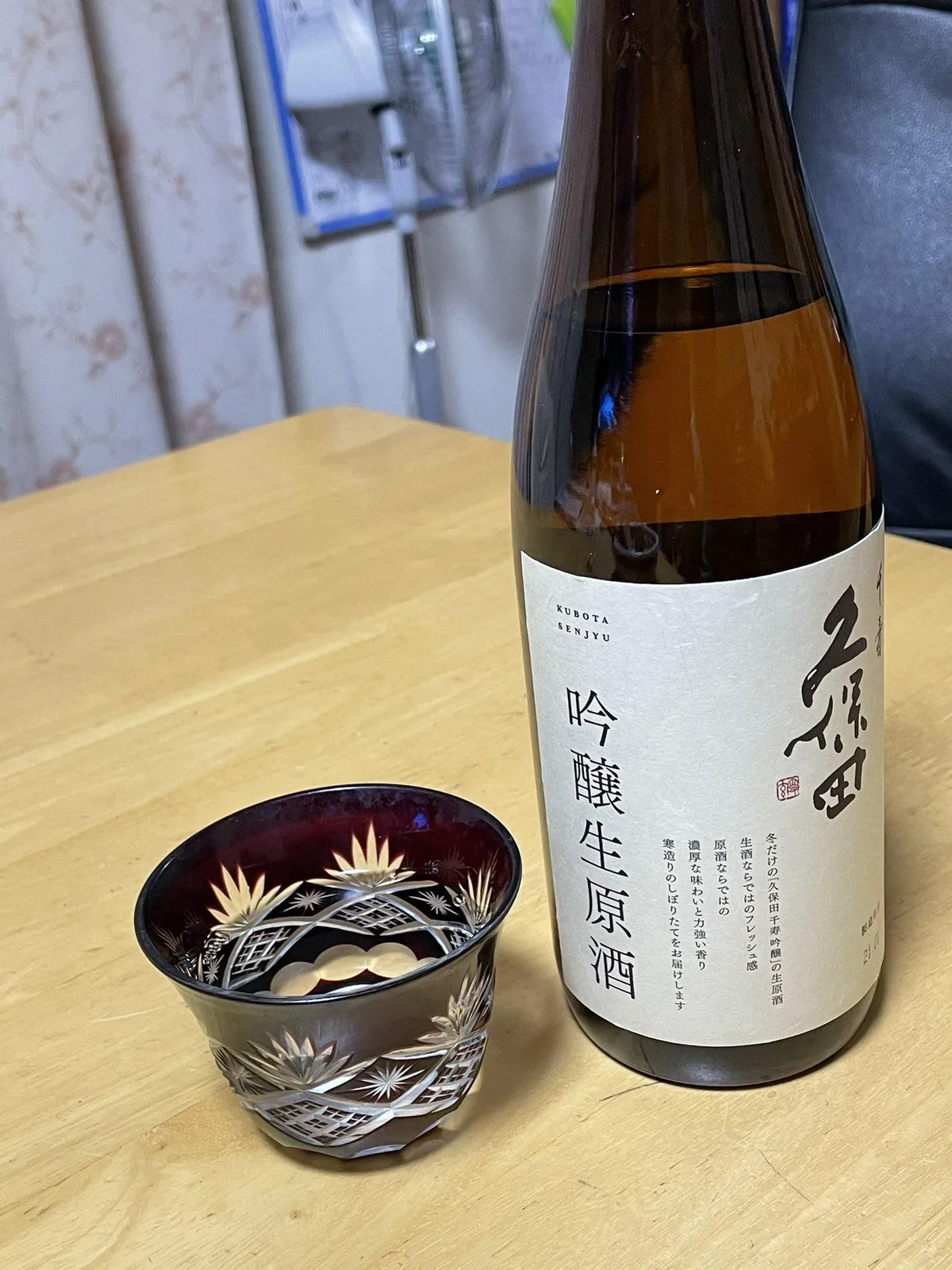 テーブルに置かれた久保田 千寿 吟醸生原酒のボトルと、お酒が注がれた紫色の切子グラス