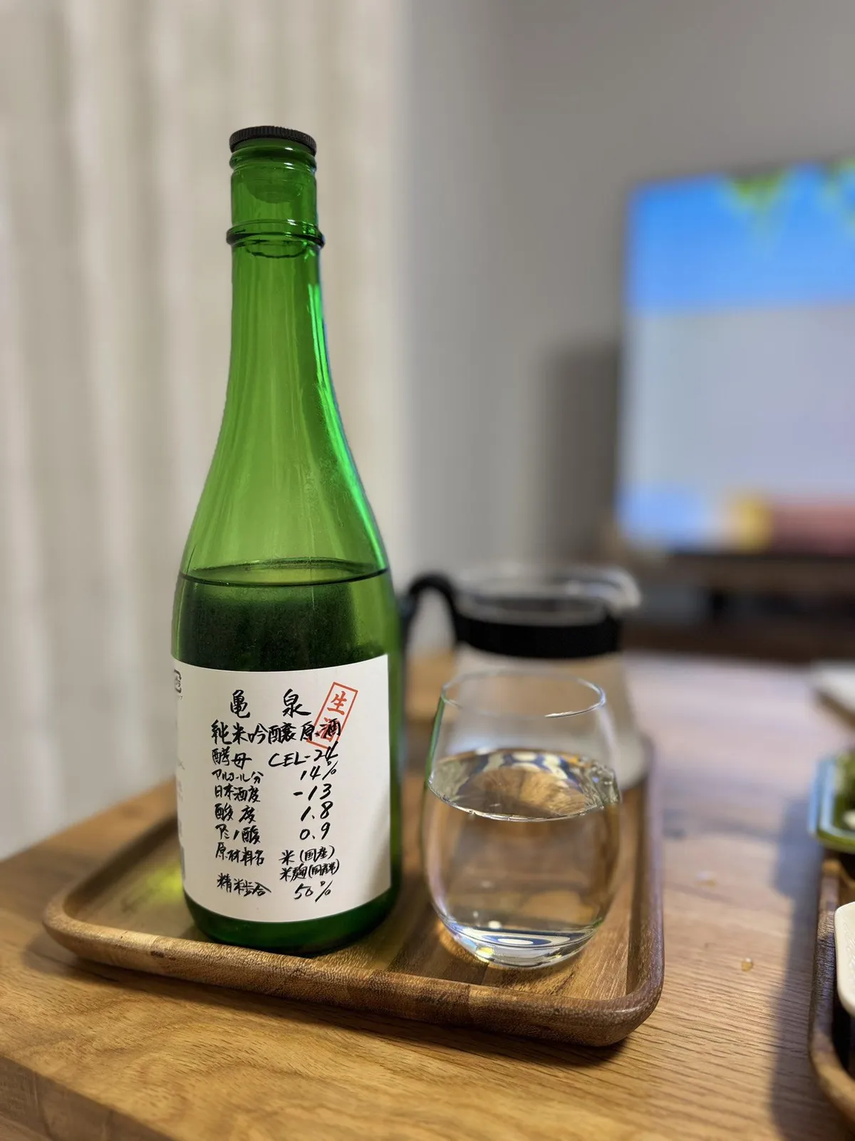 木のトレイに乗せられた亀泉のボトルと、お酒が注がれたグラス
