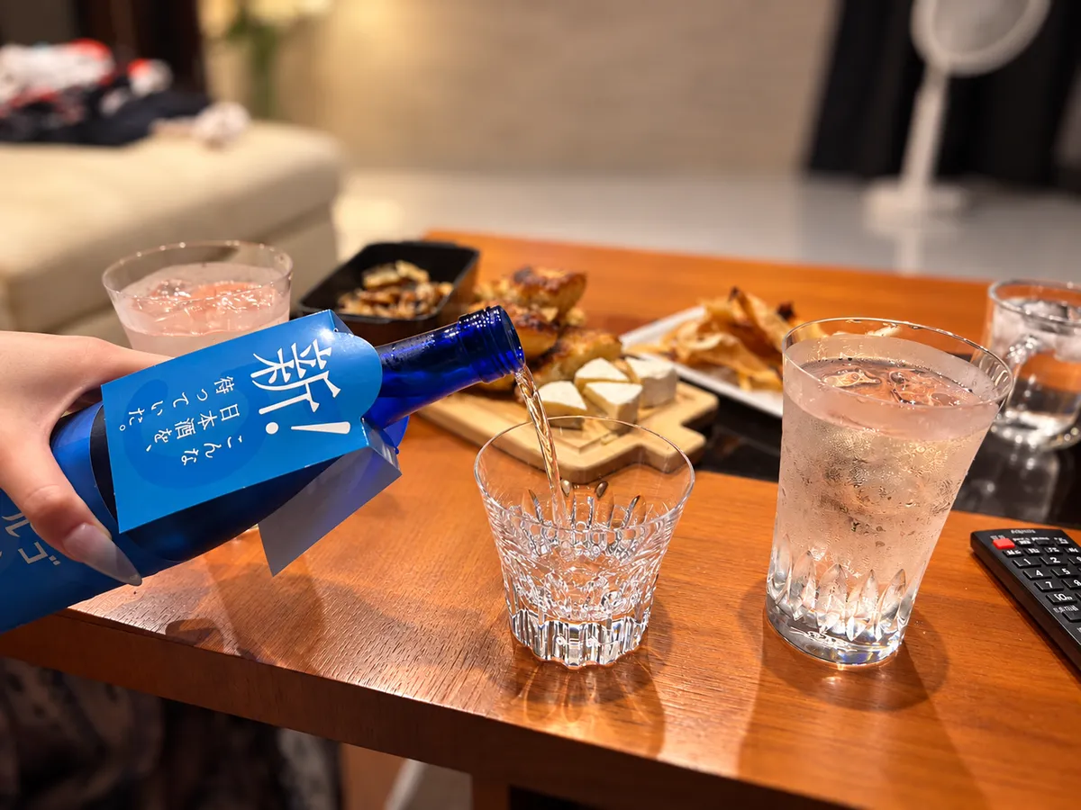 クリスタルグラスに注がれる日本酒とテーブルに並ぶおつまみ
