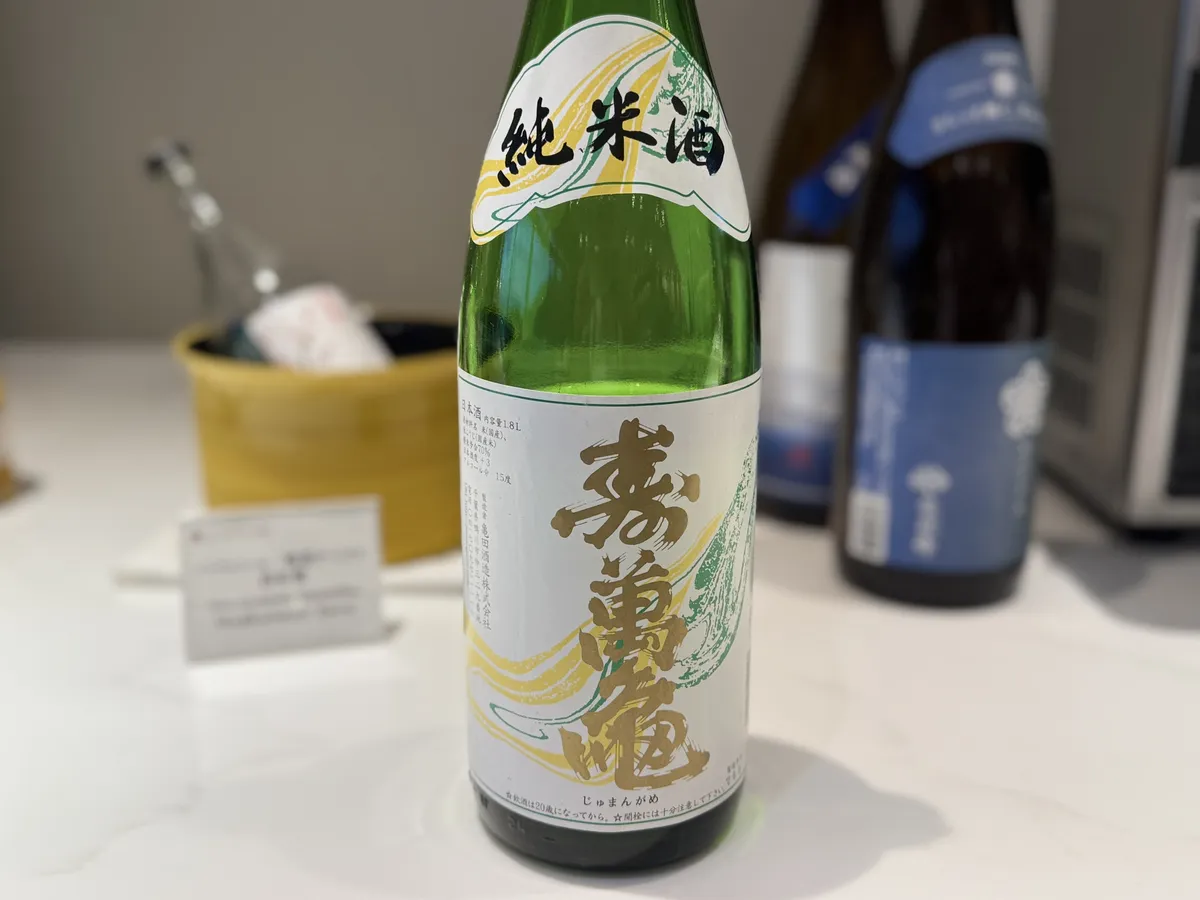 純米酒 寿萬亀のボトル全体。白地に金色の文字が映えるラベルが特徴的