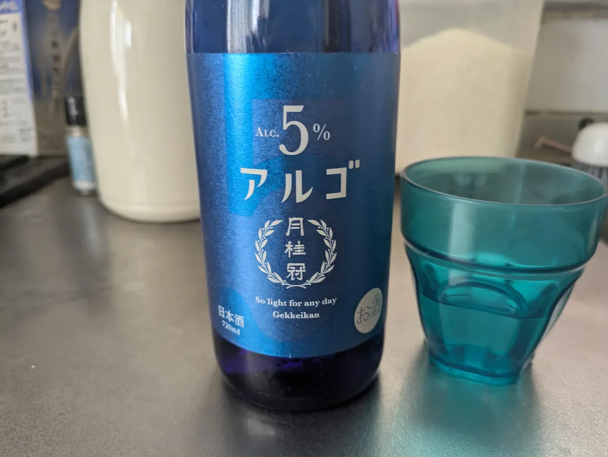 鮮やかなブルーのボトルに白文字で5%と書かれた月桂冠 アルゴ 日本酒5.0と、青いグラス