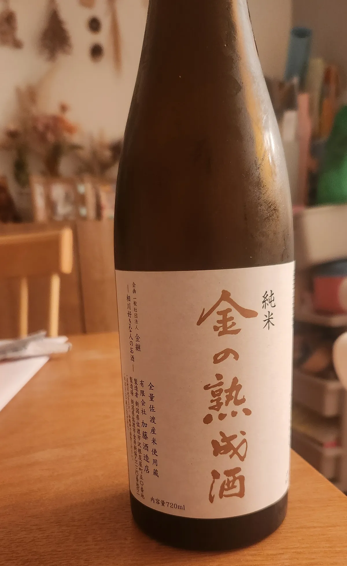 金の熟成酒のボトル。落ち着いた茶色の瓶に温かみのある和紙風のラベルが貼られている
