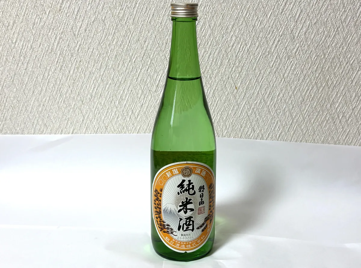 朝日山 純米酒のボトル全体。緑色の瓶に伝統的なデザインのラベルが貼られている