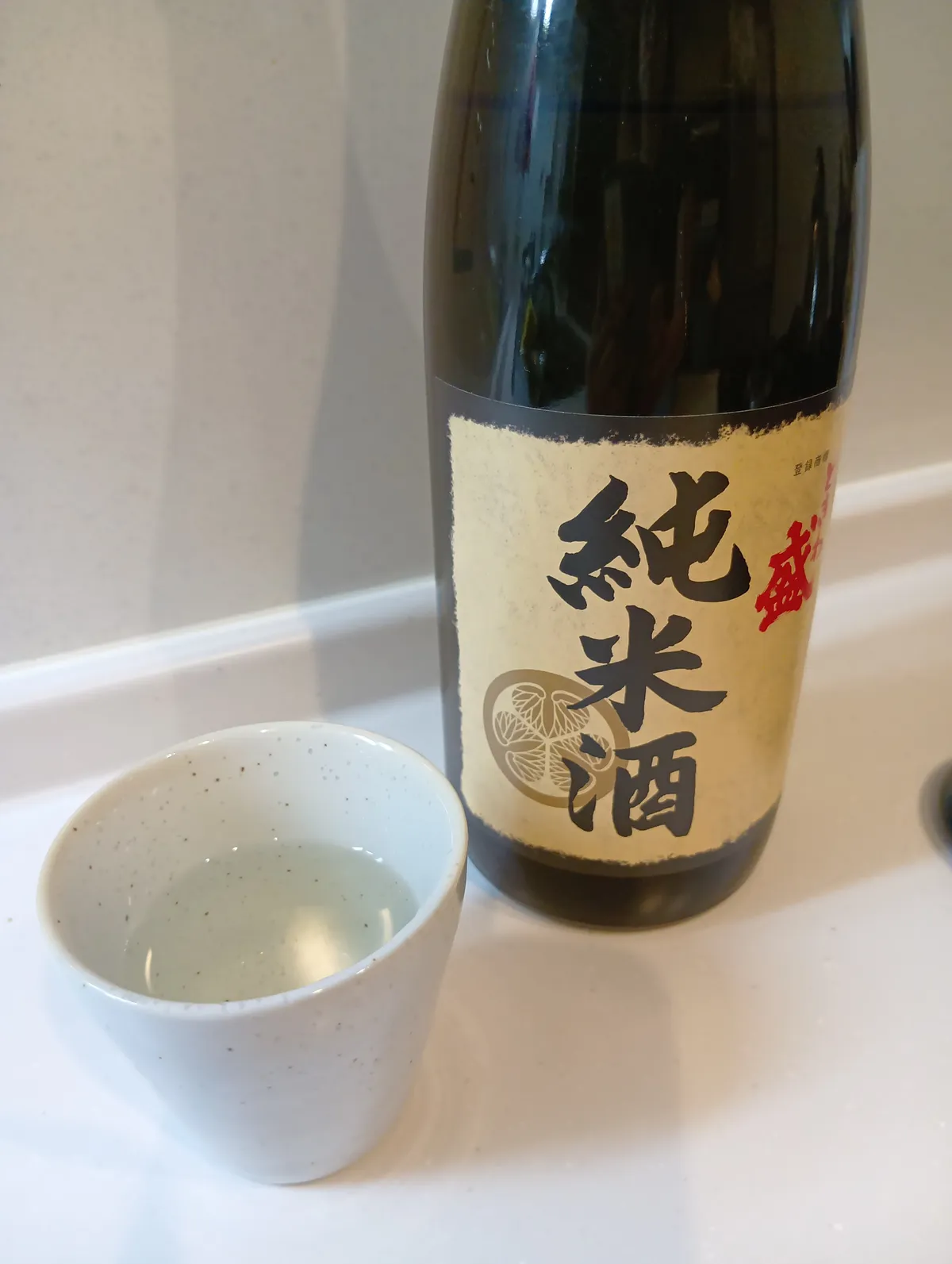 白いお猪口に注がれたときわ盛 純米酒とボトル。透明感のある佇まい